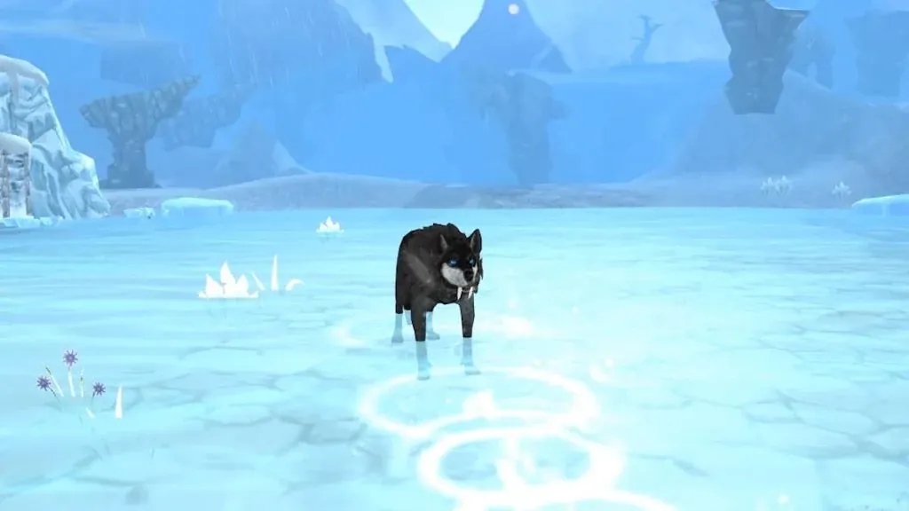 A dark brown wolf standing alone on cracked pale blue ice with snowy cliffs behind it